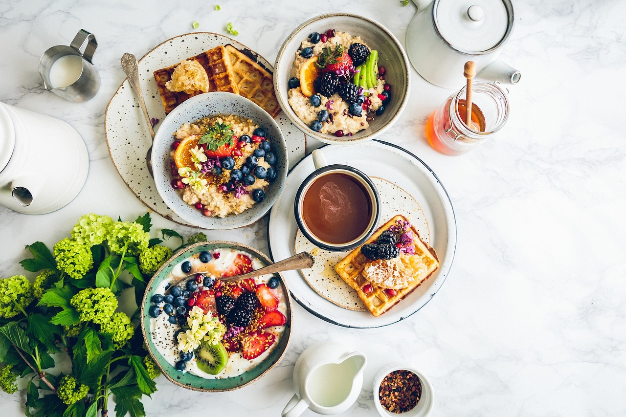 Gedeckter Frühstückstisch mit Obst, Porridge und Waffeln